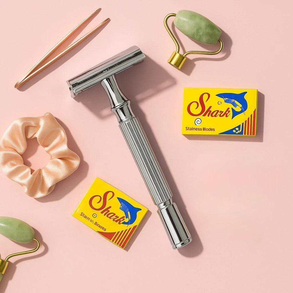 Silver safety razor with two boxes of Shark brand razors on a pink background