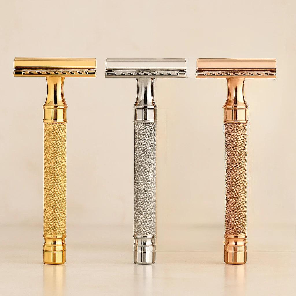 Three razors with gold, silver, and rose gold handles on a beige background